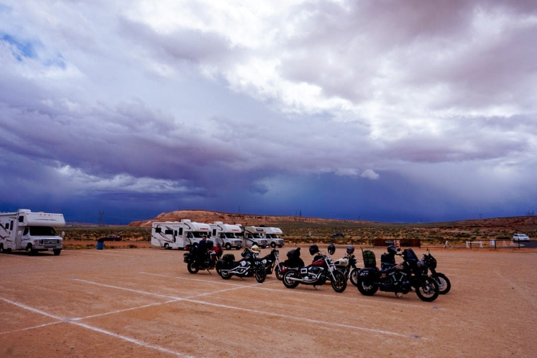 A dark sky above a row of parked motorcycles and RVs. 