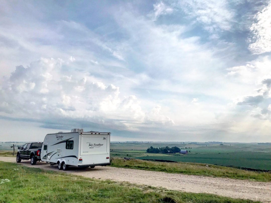 RV parked on a gravel road surrounded by scenic farmlands