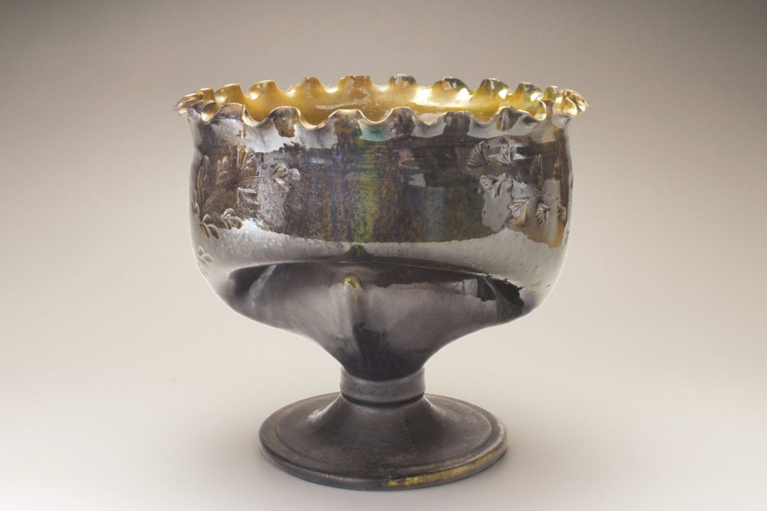 An ornately decorated silver cup on a foot. 