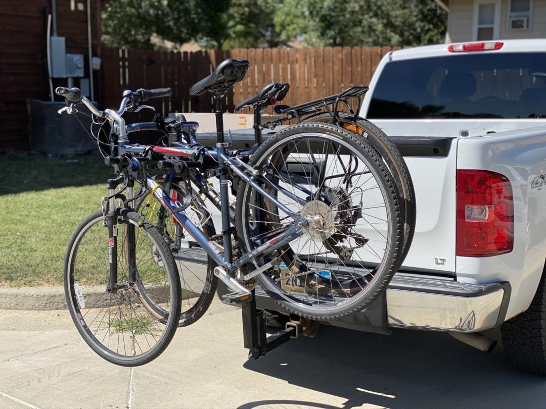 Two bicycles installed on a bike rack behind a truck
