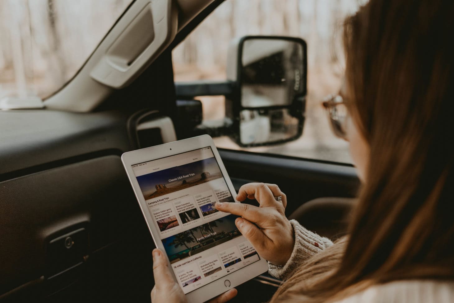 Woman searching for road trip inspiration on iPad while in car
