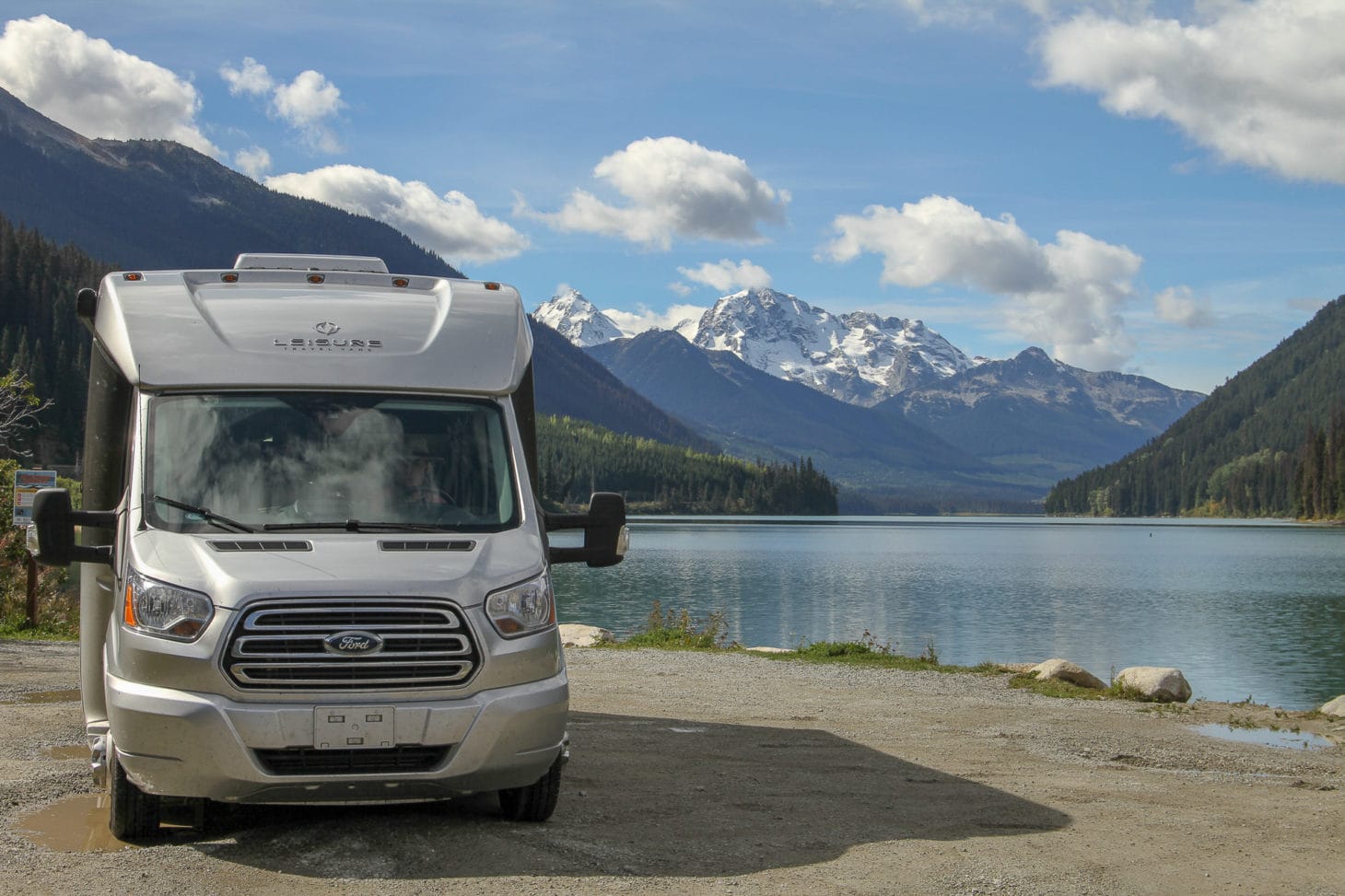 Motorhome parked next to lake with mountain backdrop