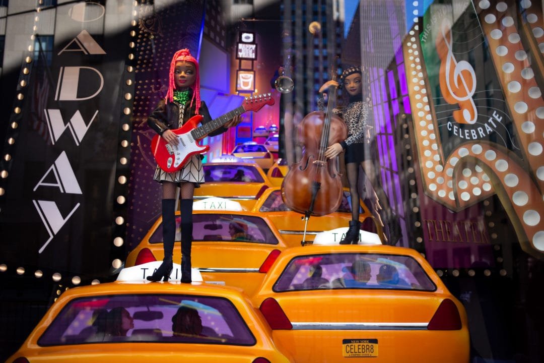 Perched atop taxis in Times Square, two musicians make music. A title on the window declares, “No jazz club, no problem. We’ll just take our music to the streets.” 
