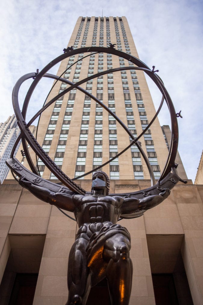 a large bronze statue of atlas carrying a globe on his shoulders outside of rockefeller center