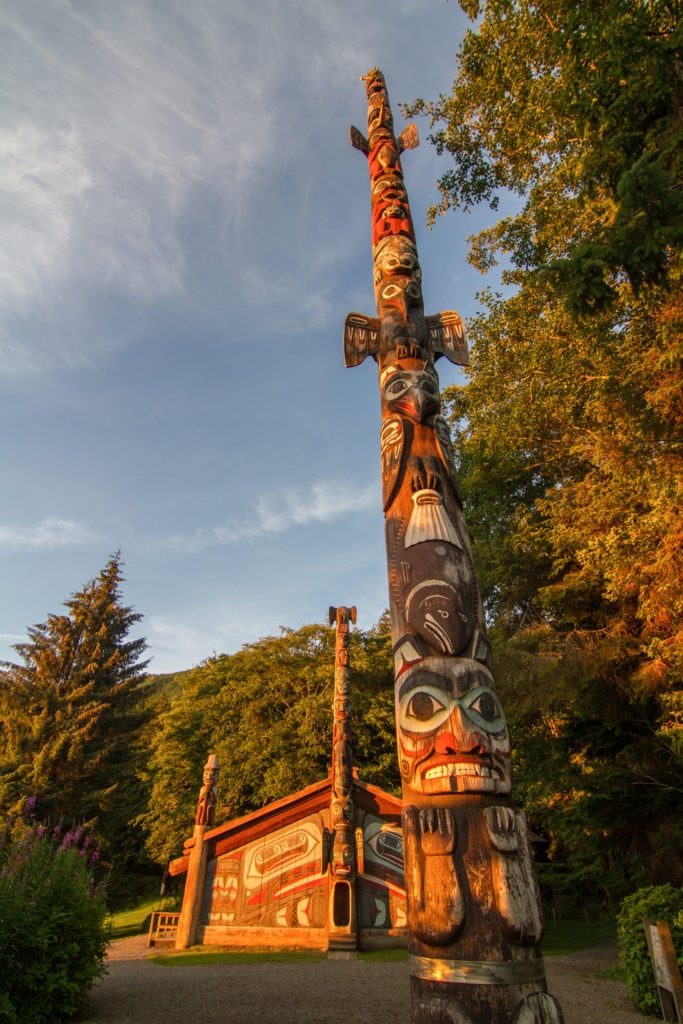 An intricately carved totem stands tall against a blue sky.