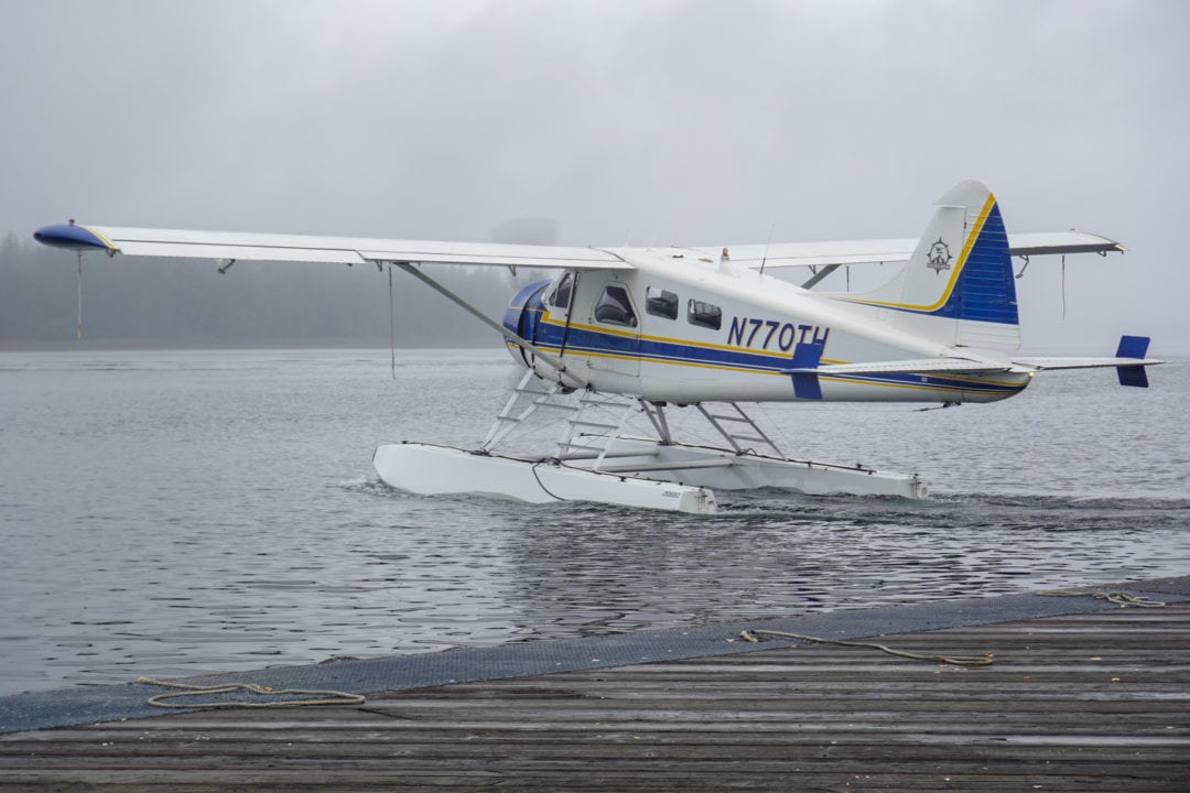 A float plane taking off from the water, surrounded by fog