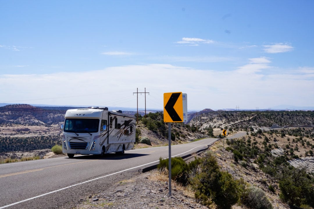 A motorhome driving on a scenic road with mountains in the background