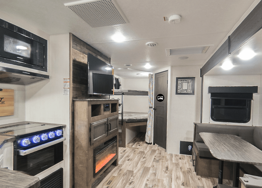 Interior of RV living space with kitchen, living area, and double over double bunks