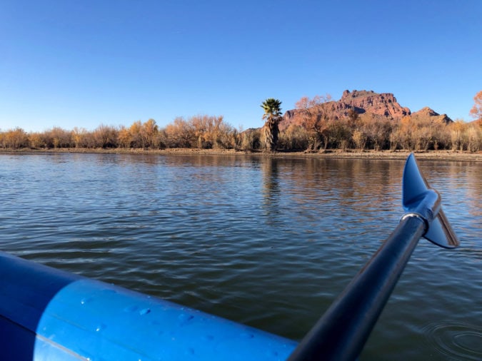 View from kayak on river looking out at river and red rock mountains in the distance
