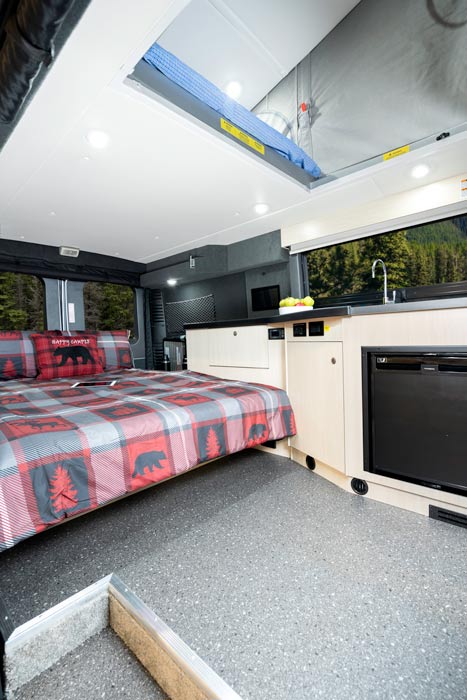View of transformed dinette to bed in the rear of a Class B van with view of pop-up bed
