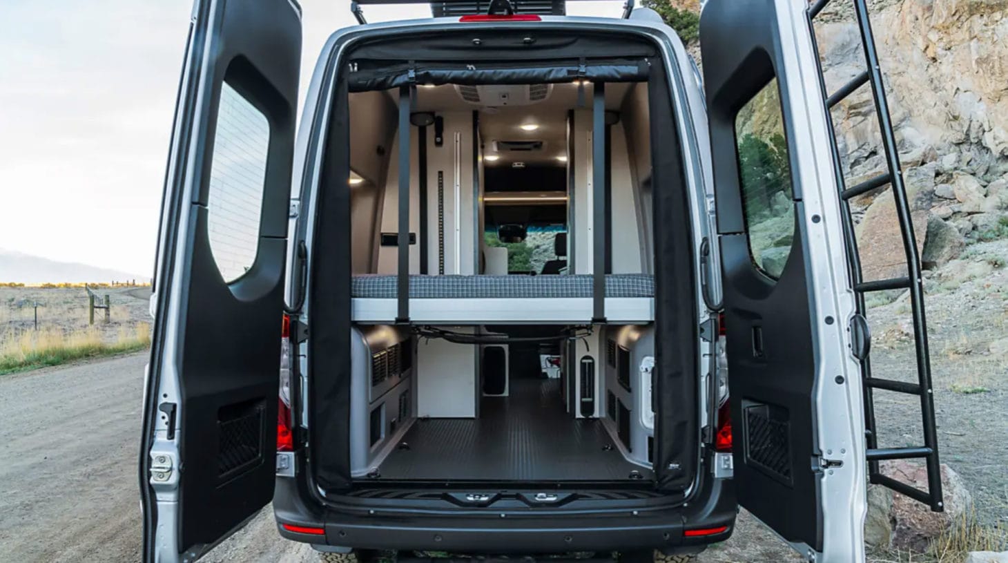 Back view of converted van with bed on lifts for storage and living space