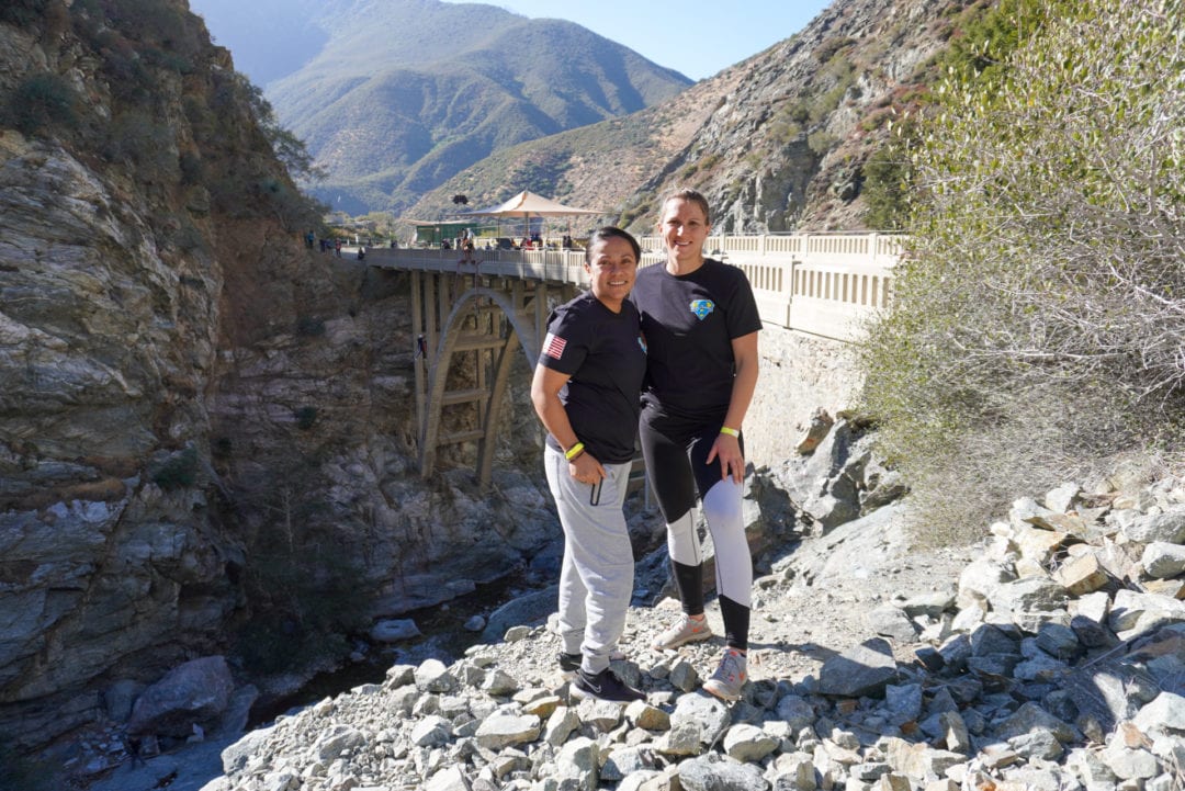 Two women smiling at the camera with the bridge behind them