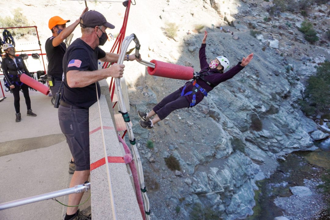 A woman does a backwards bungee jump off a bridge. 