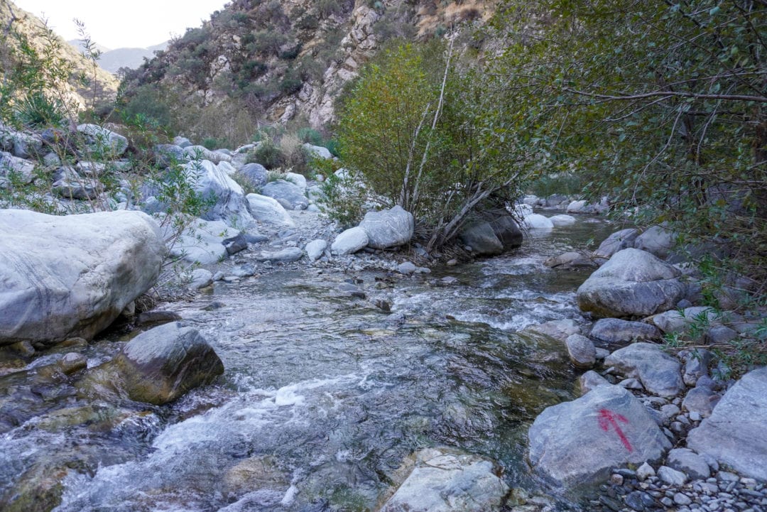 A river crossing on a hike, the direction marked with a red arrow on a rock 
