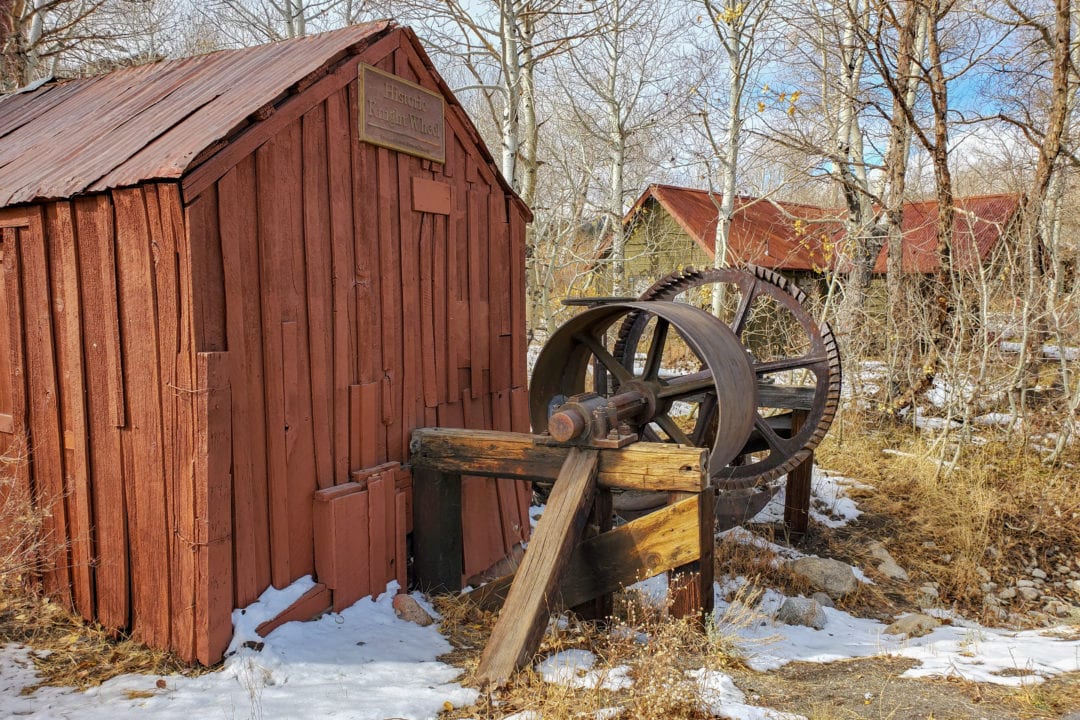A red wooden barn and metal water wheel