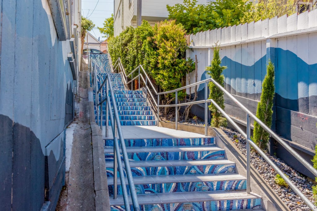 A waterfall mosaic swirls in shades of blue from cobalt to aqua, splashed across a stairway