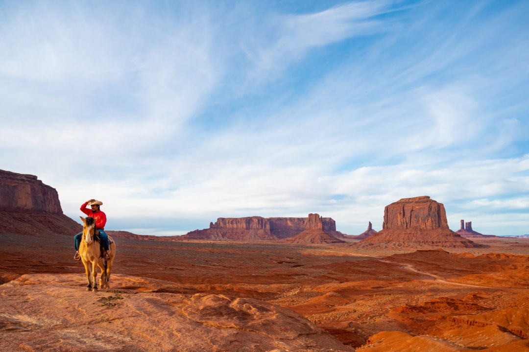 a scenic view of sandstone outcroppings with a cowboy on a horse