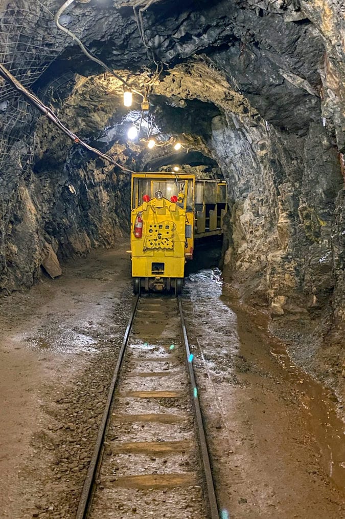 A bright yellow train coming through a mine tunnel