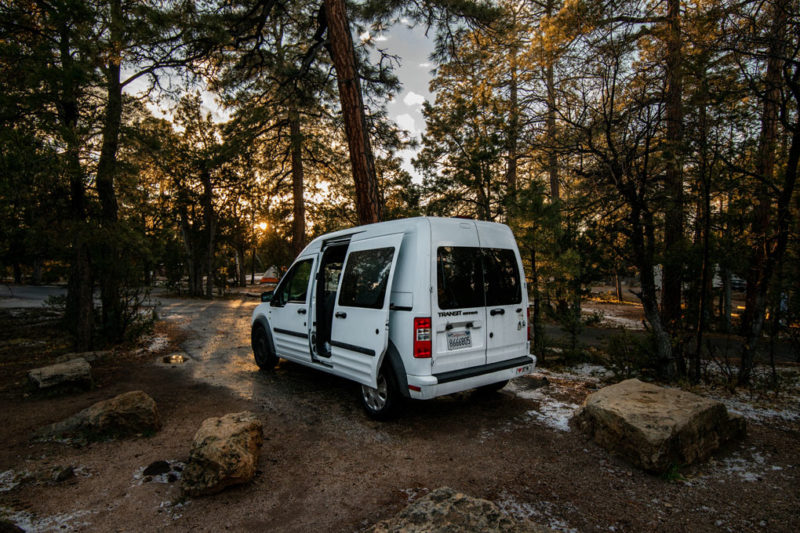 White Ford Transit van parked in a wooded forest area