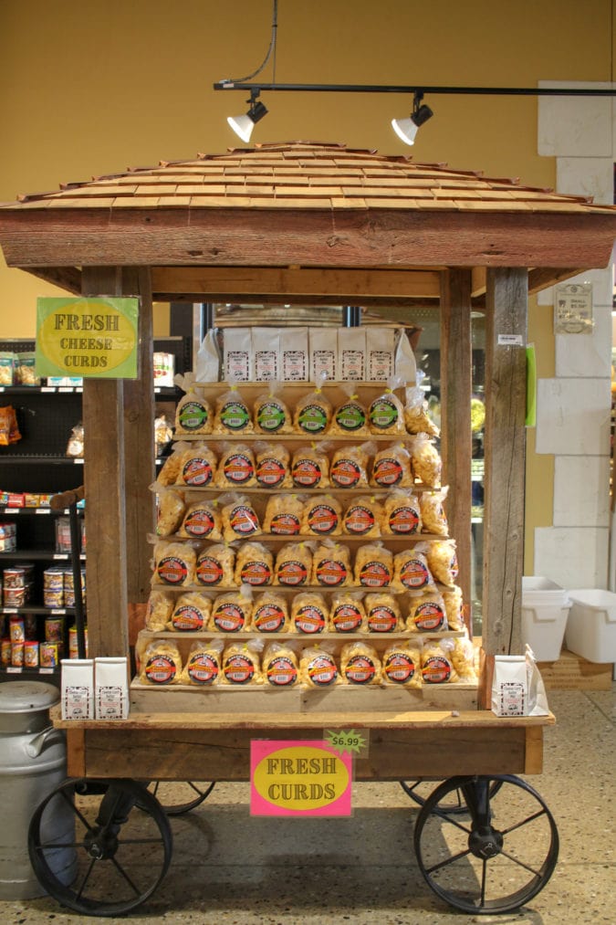 a wooden display with bags of cheese curds and signage that says "fresh cheese curds"