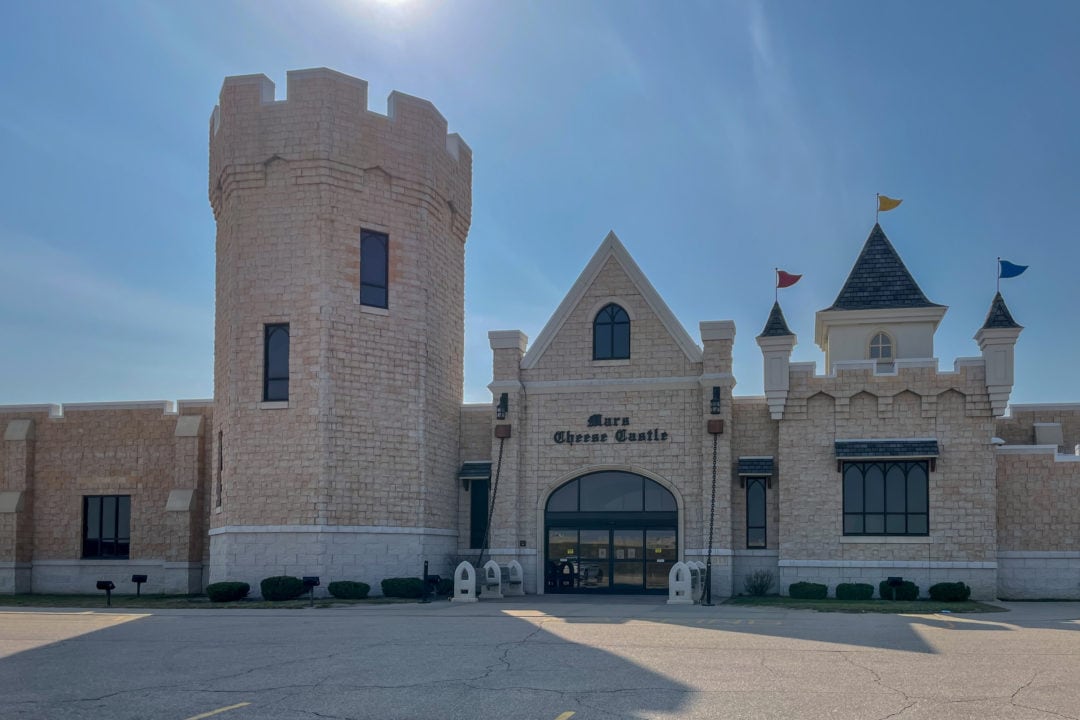 a beige stone castle building with turrets and pennant flags