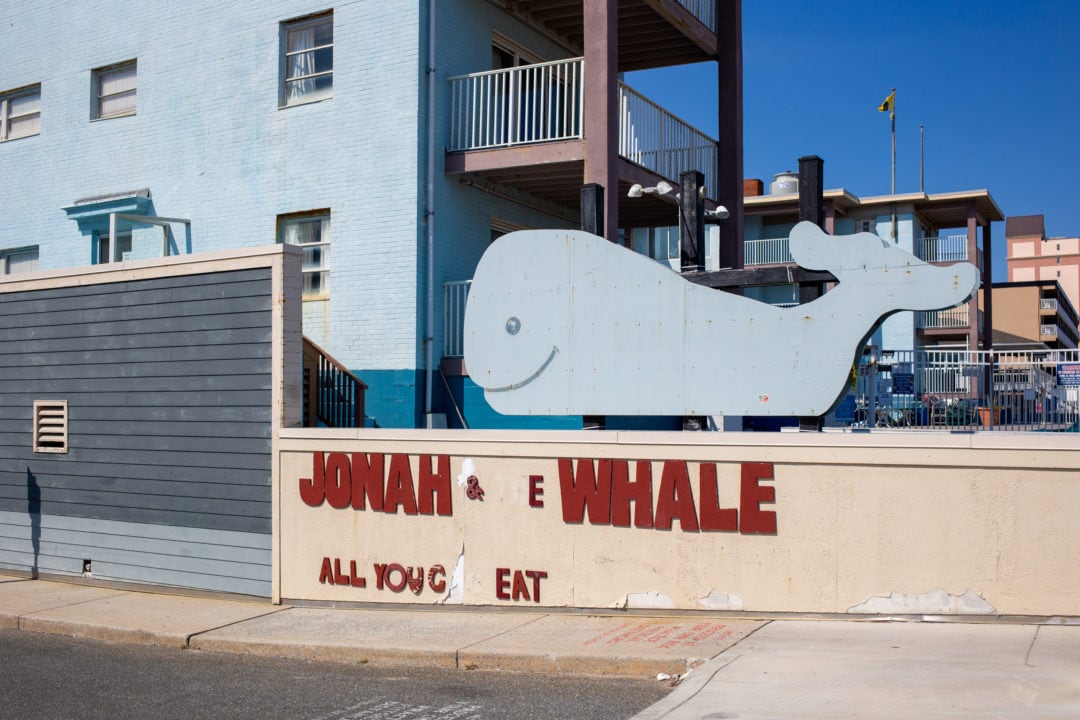 A blue building with a whale and decrepit sign out front 