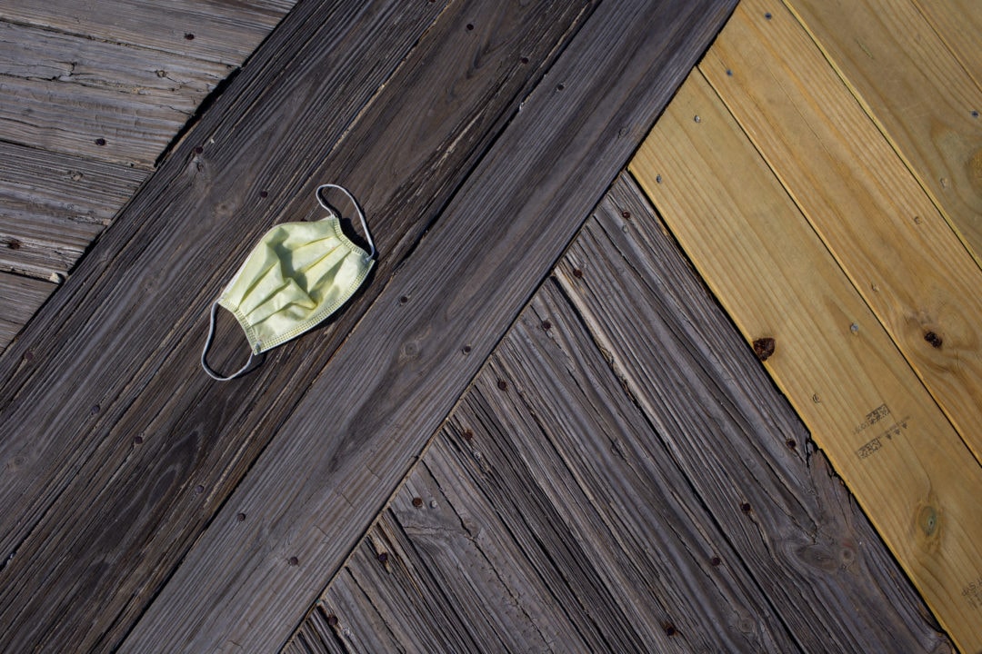 a yellow disposable face mask on a wooden boardwalk