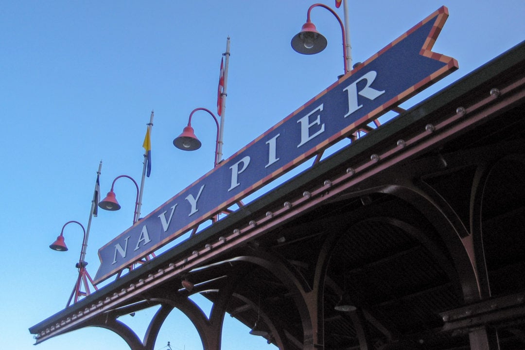 a sign that says 'navy pier' with overhanging lights