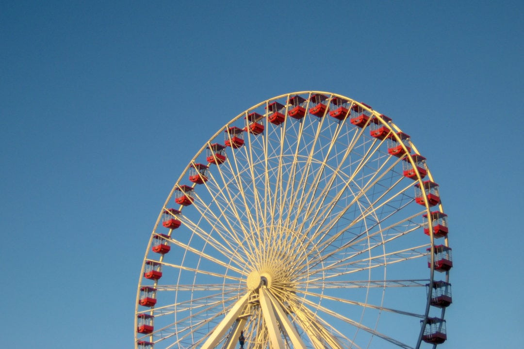 a white ferris wheel with red cars set against a clear blue sky
