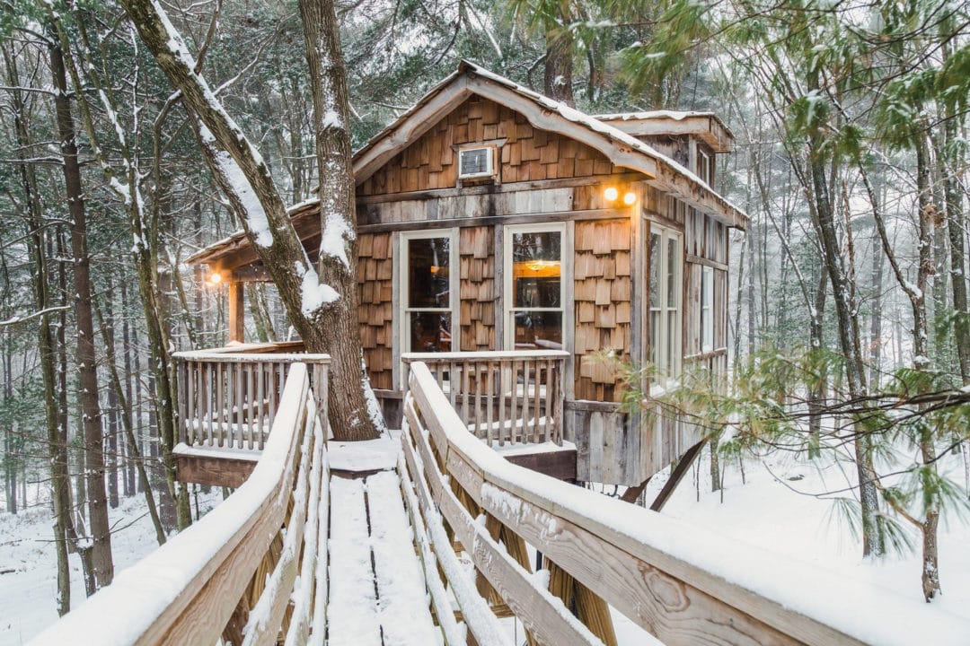 A wood shingled treehouse in the snow
