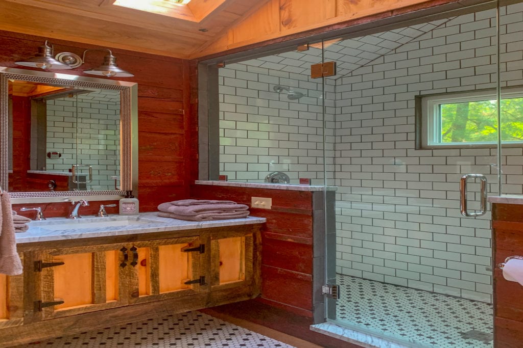 A wood paneled and white tiled bathroom with walk in shower