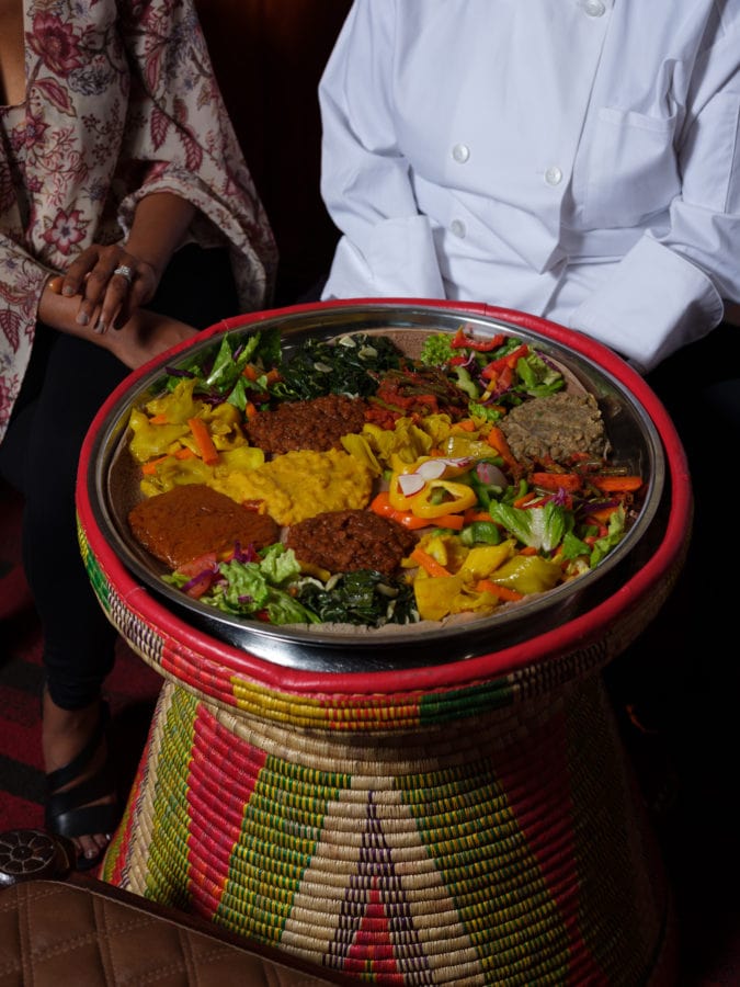 Close up of various colorful Ethiopian food on large woven platter 