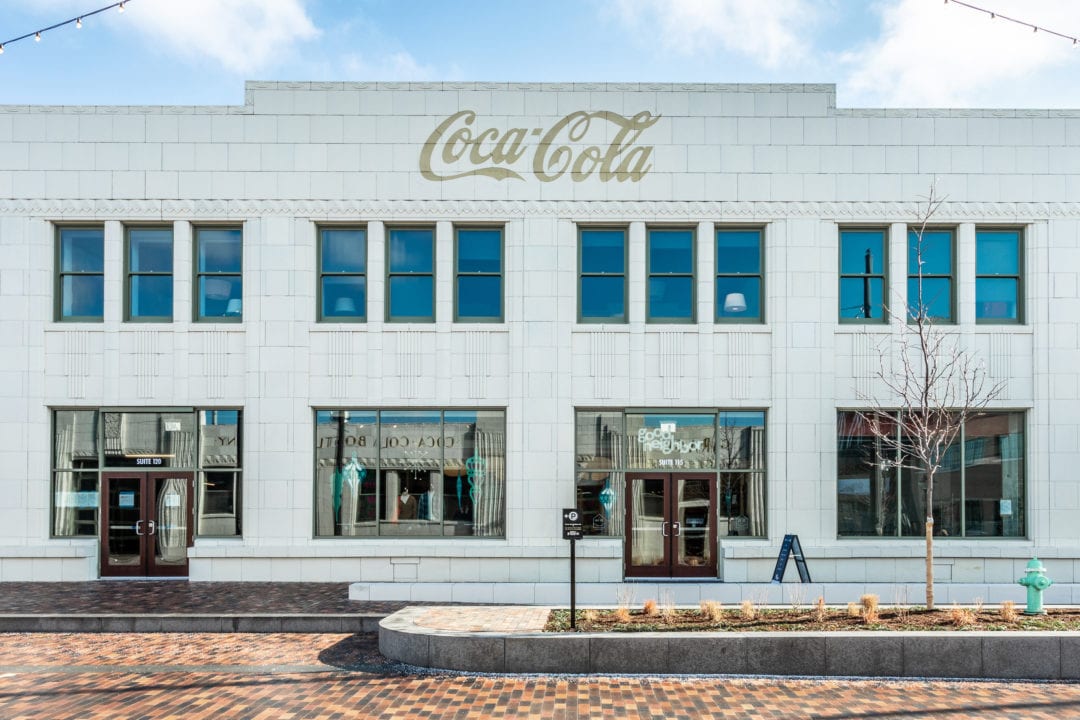 a white art deco building with gold coca-cola logo