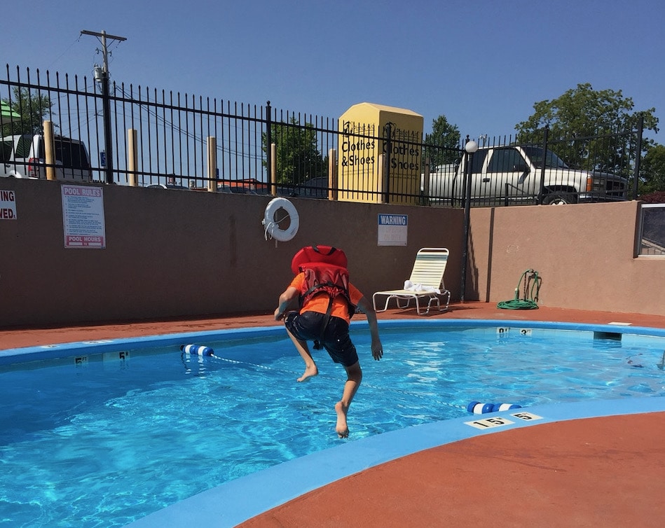 Boy in life vest jumping into pool