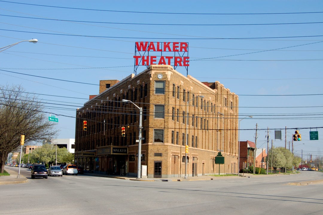 a beige art deco style building set against a blue sky topped with a red sign that reads "walker theatre"