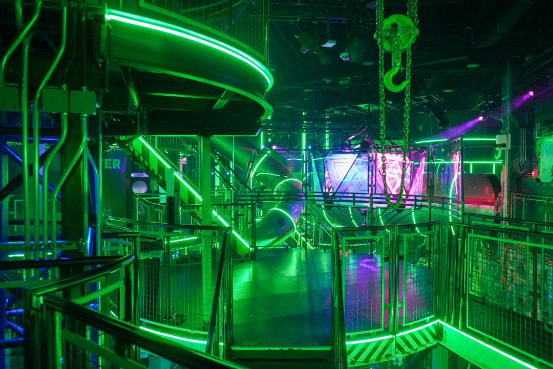 A green-lit room with multiple levels of slides and platforms