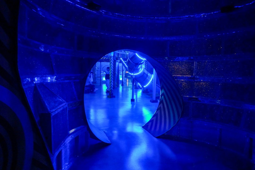 A blue room with a tunnel that leads into a bigger space.