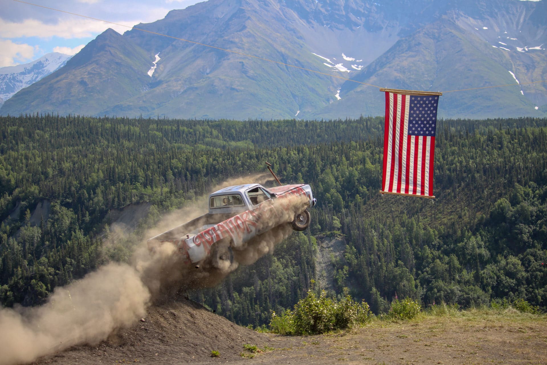 a truck drives off a cliff next to an american flag