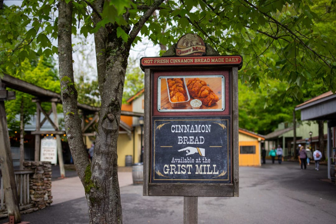 a sign advertising cinnamon bread available at the grist mill with a hand pointing left