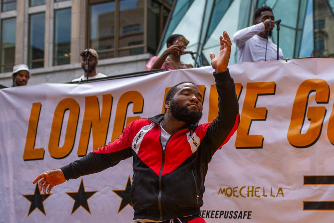 A Black man dances in front of a banner that says "Long Live GoGo"
