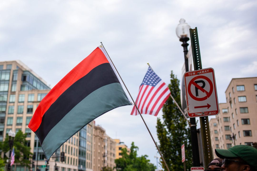 The red, black, and green Pan-African flag flies next to an American flag
