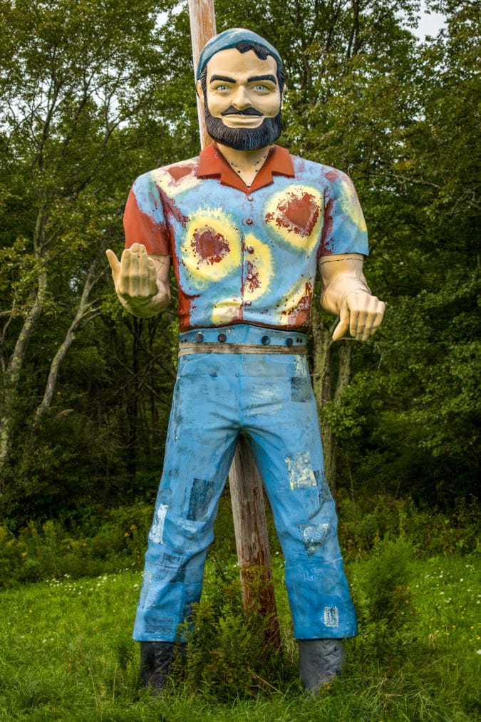 a fiberglass muffler man with a tie die shirt and patchwork jeans