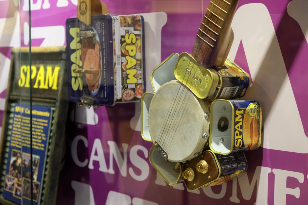 a museum display featuring a banjo made from spam cans