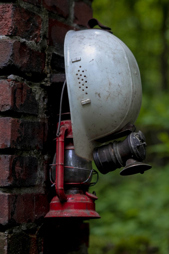 a coal miners helmet hangs on a brick wall