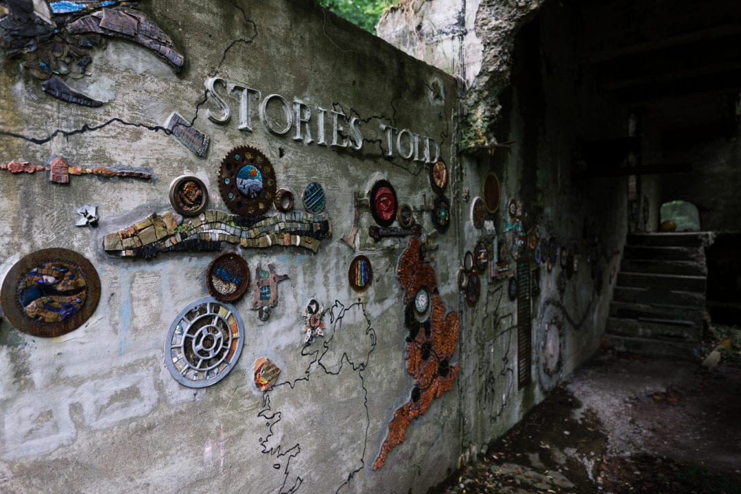 mosaics cover a crumbling concrete wall with the words "stories told"