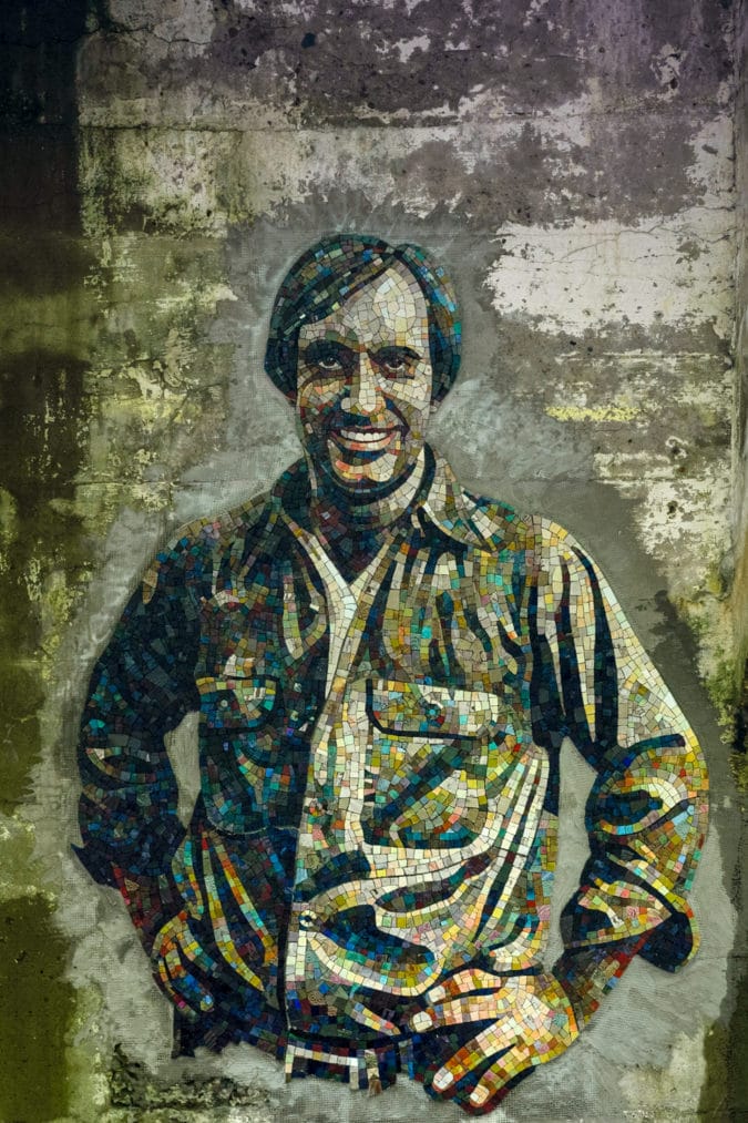 a mosaic portrait of a smiling man with hands on his hips