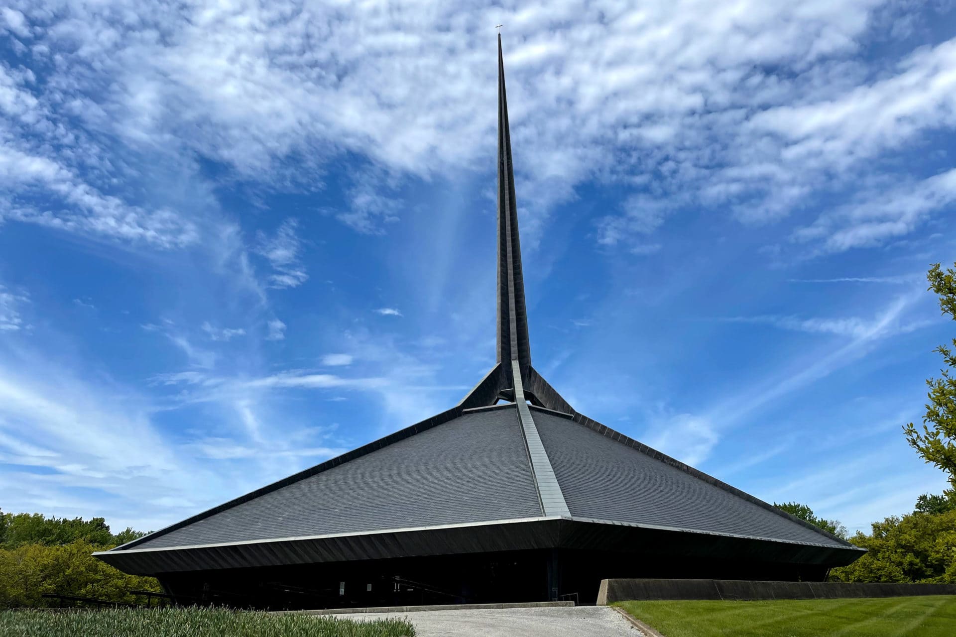 a modern church with a sharp black steeple set against a blue sky