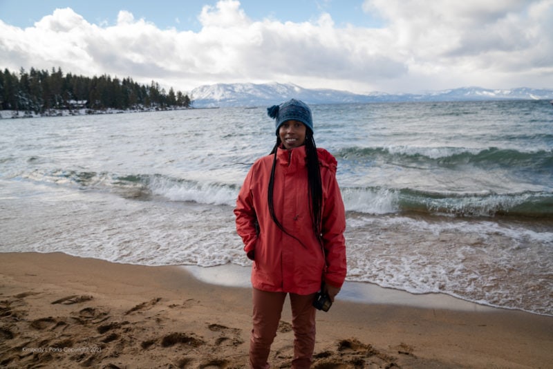 A woman wearing warm clothes standing in front of a wavy ocean