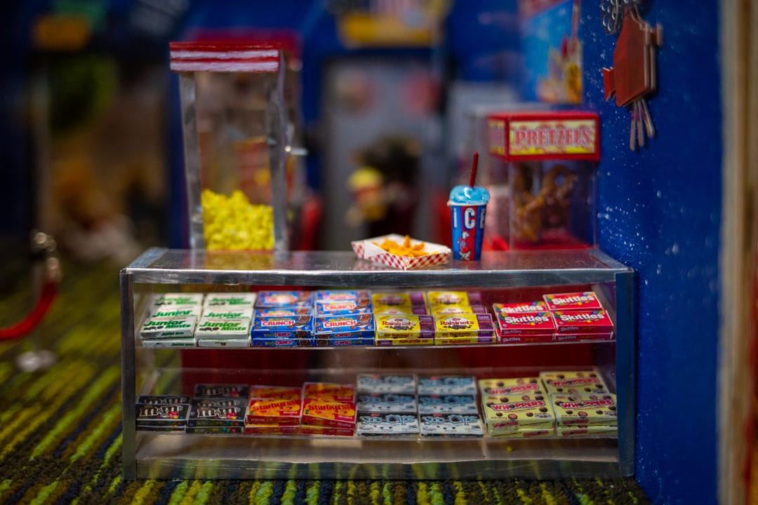 A miniature movie snack bar with popcorn, an icee and boxes of candy