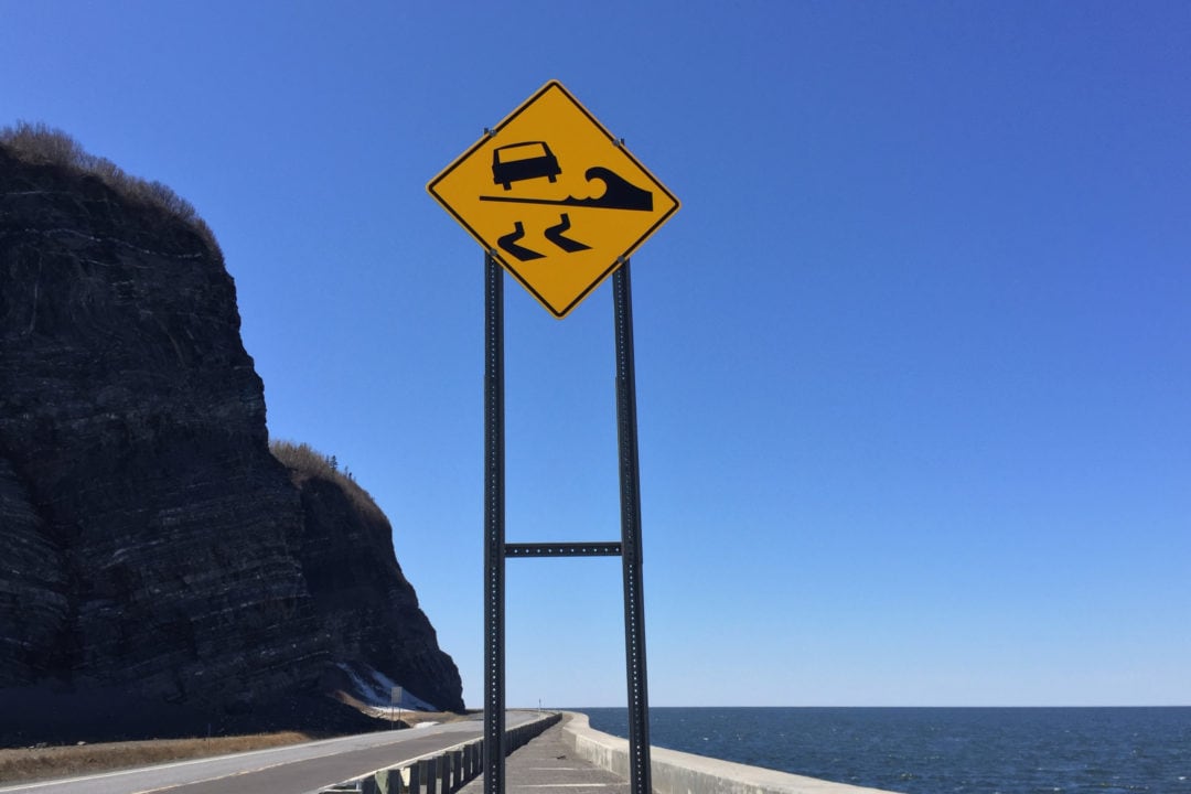 a road sign warning of waves on the roadway